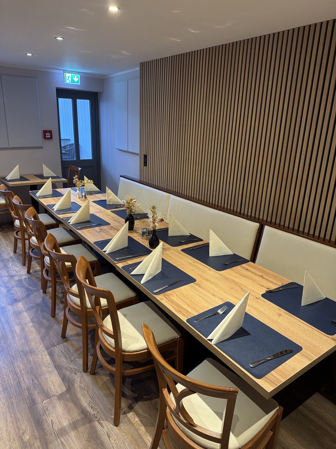 Separater Veranstaltungsraum mit gedeckter Tafel, Sitzbank und Holzwand