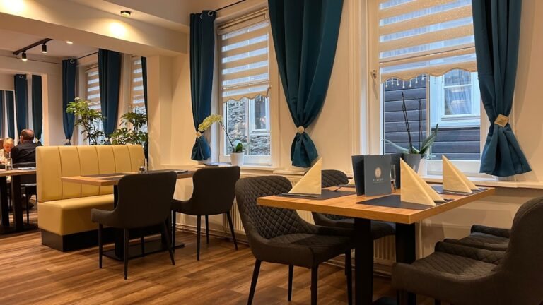 Gedeckte Tische, warme Holztöne und blaue Vorhänge im Restaurant Platon